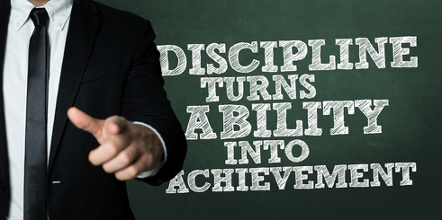Business man pointing with the text: Discipline Turns Ability Into Achievement